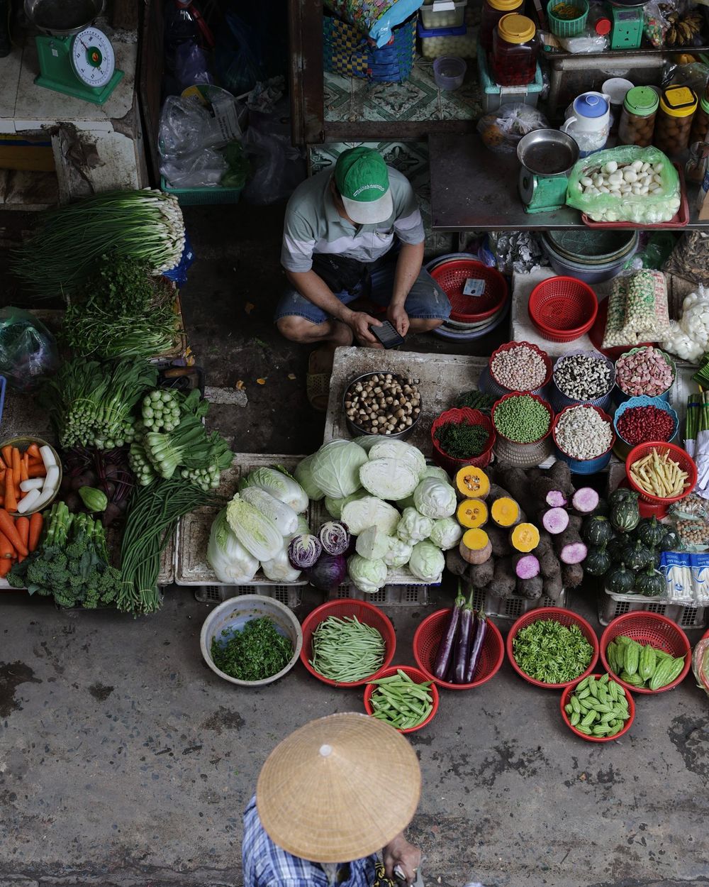Sạp rau ở chợ nhìn từ trên xuống, nhiều loại rau bày trên mẹt
